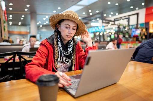 Mid adult woman using laptop at a restaurant/bar at airport