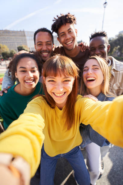 senkrecht. eine gruppe glücklicher freunde, die an einem frühlingstag für ein selfie posieren, während sie gemeinsam im freien feiern - selfie stock-fotos und bilder