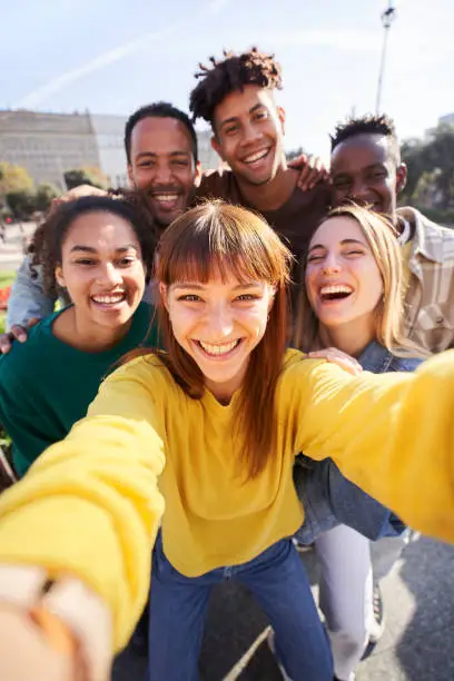 Photo of Vertical. Group of happy friends posing for a selfie on a spring day as they party together outdoors