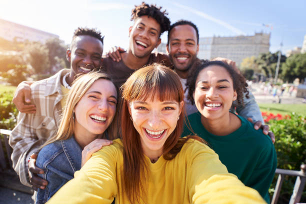 Group of happy friends posing for a selfie on a spring day as they party together outdoors Group of happy friends posing for a selfie on a spring day as they party together outdoors. Group of multicultural friends having a good time together on the weekend. selfie madrid photos stock pictures, royalty-free photos & images