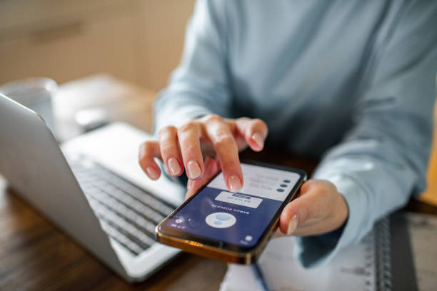 istock Young woman using a banking app on her phone while working from home 1479799881