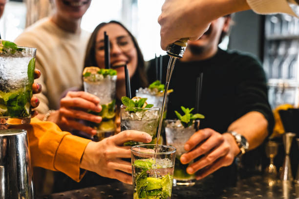 バルコニーバーでカクテルを持ち、飲む幸せな友人のグループ – モヒートドリンクでパーティーディスコを楽しむ若者 – お祝いとライフスタイルのコンセプト – 若者文化 - friendship relaxation cocktail nightclub ストックフォトと画像