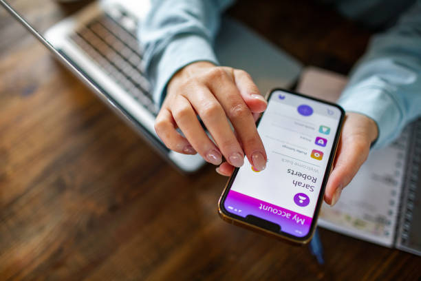 istock Young woman using a banking app on her phone while working from home 1479800468