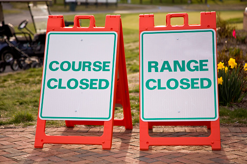 Signs informing golf facilities are closed for the day.