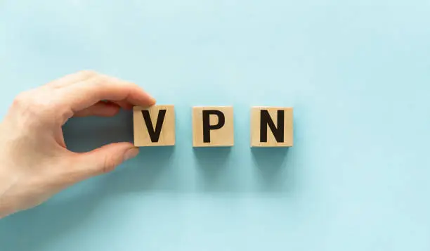Photo of Hand holding wood cube block with VPN text. VPN - short for Virtual Private Network