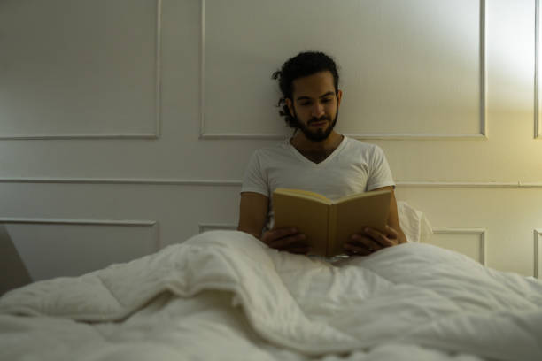 istock Attractive man in bed enjoying a book 1479808625