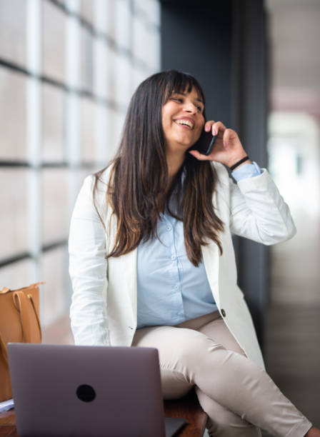 istock Cheerful businesswoman using cell phone in office lobby 1479810411
