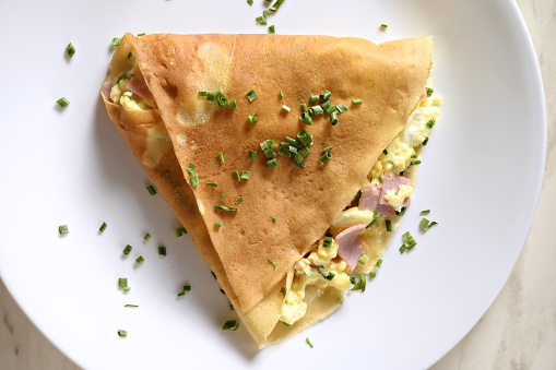 ham and cheese omelette crepe on a white plate