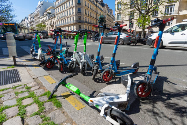 Rental electric scooters parked on the side of the roadway in Paris, France Paris, France - April 4, 2023: Rental electric scooters from various companies parked on the side of the roadway in the Champs-Elysees district of Paris, France lime scooter stock pictures, royalty-free photos & images