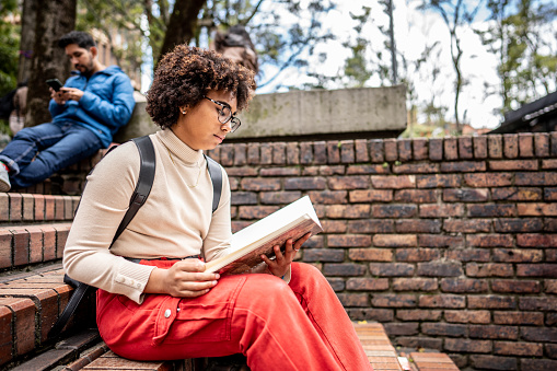 Young university student studying on stairs outdoors