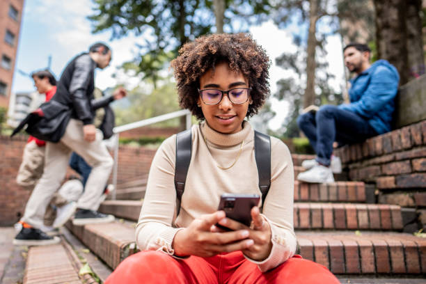 Young university student using mobile phone on stairs outdoors Young university student using mobile phone on stairs outdoors teenager adolescence campus group of people stock pictures, royalty-free photos & images