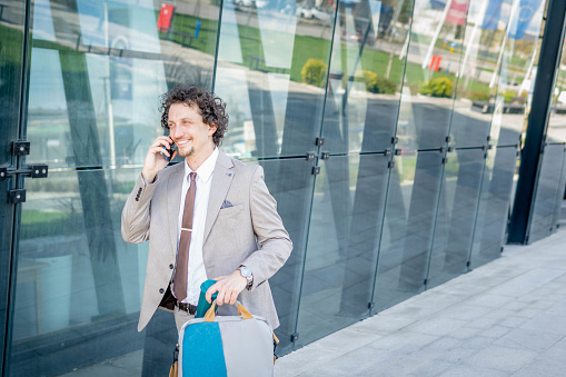 Successful businessman in front of a office building talking on his smartphone
