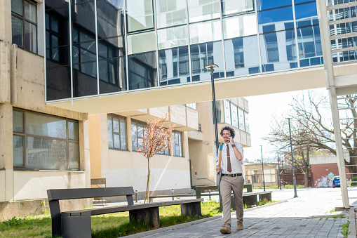 Successful businessman in front of a office building talking on his smartphone