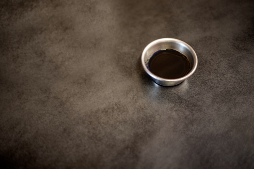 Soy sauce is in a metal bowl on a gray background. still life photography.