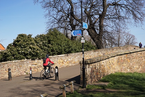 Haddington, Scotland - 3 April 2023:  A cyclist is about to cycle across the  Old Nungate Bridge that crosses the river Tyne in Haddington on a sunny spring day.