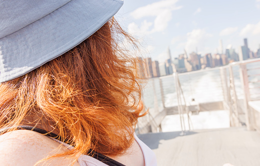Young woman with red hair is riding ferry on East River in New York City.