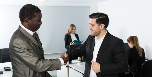 Strong handshake of two businessmen as sign of reliable partnership in modern office