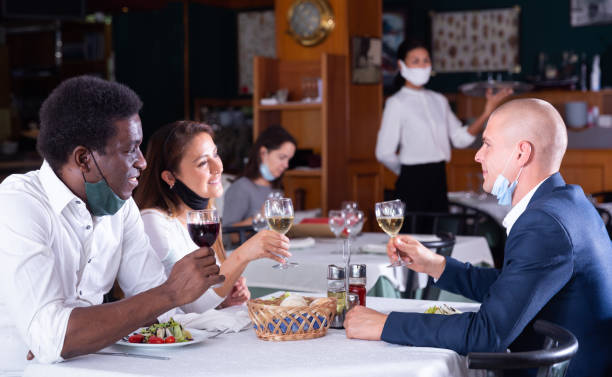istock Cheerful people in masks having dinner in restaurant 1479854582