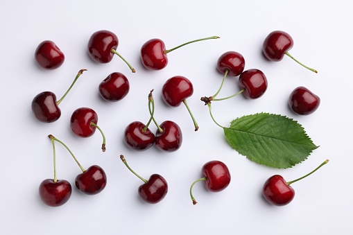 Many sweet ripe cherries on white background, flat lay