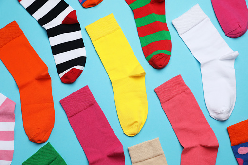 Many different colorful socks on light blue background, flat lay