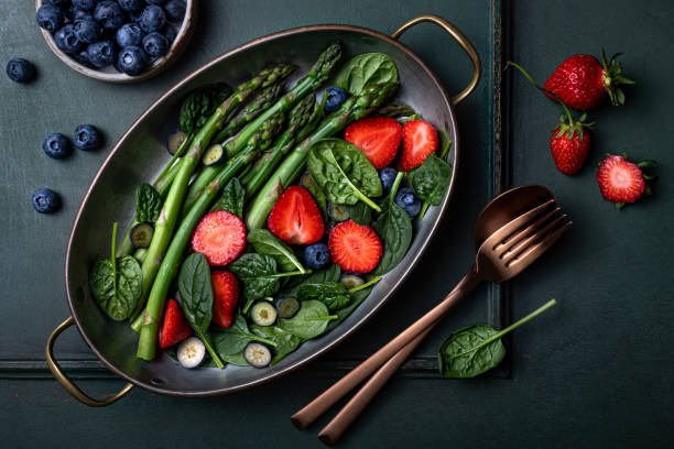 Green asparagus, strawberry, spinach, blueberry salad. Top view stock photo