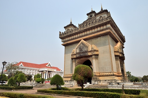 Vientiane, Laos.\nThe Patuxay is 45 meters high and 24 meters wide. It is located in the center of Vientiane, near the Prime Minister's Office. Construction began in 1960 and was largely completed in 1969. It looks like the Arc de Triomphe in Paris, France, from a distance, but on the base of its arch are typical Lao temple carvings and decorations, exquisite carvings full of Buddhist colors, showing the traditional national culture and art of Laos.\nThe Lao Prime Minister's Office is located next to the Arch of Triumph, and its architectural style is highly characteristic of Lao nationality