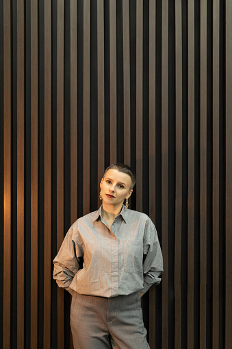 atmospheric portrait of a strong woman with a short haircut against a wall with vertical wood panels.