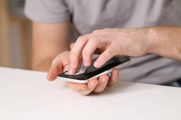 istock man cleans phone screen stick protective tempered glass. Broken glass 1479880534