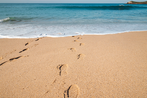 Footprints in the sand from a man sinking into the deep Atlantic Ocean on the sandy beach of Praia da Ilha do Pessegueiro near Porto Covo, western Portugal.