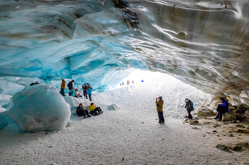 Whistler, British Columbia, Canada - February 8 2022 : Skiers and snowboarders standing at the entrance and inside of an ice cave in Whistler, BC. This is the Blackcomb Glacier Cave.
