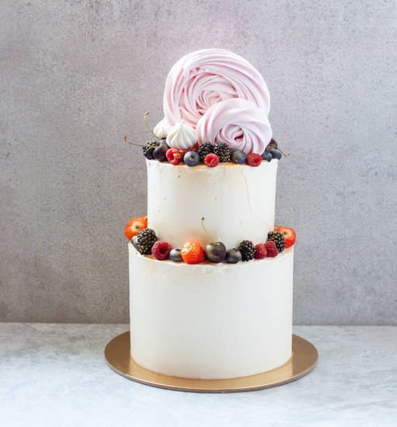 istock White tiered wedding cake with strawberries, raspberries, blackberries and blueberries on plain grey background. 1479890676
