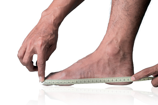 Close-up of a man measuring foot size with a measuring tape on a clipping path white background