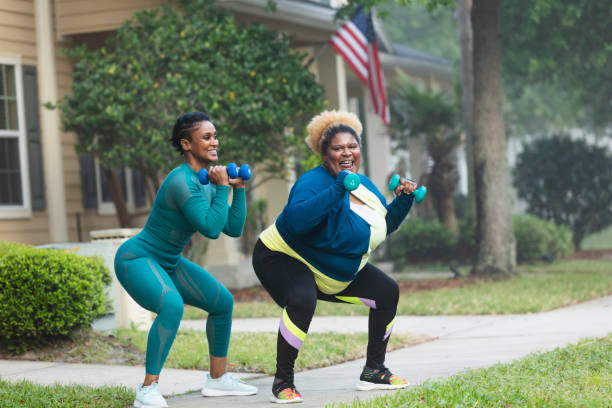 two african-american women exercising, doing squats - bending knees imagens e fotografias de stock