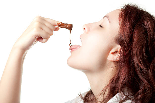 Woman Tasting Chocolate Spread Woman Tasting Chocolate Spread from Her Finger chocolate fingers stock pictures, royalty-free photos & images