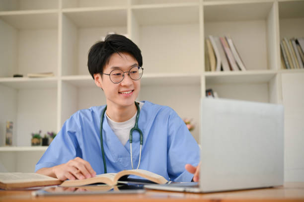 kluger junger asiatischer männlicher medizinstudent, der medizinische forschungsarbeiten im internet recherchiert - male education college student nerd stock-fotos und bilder