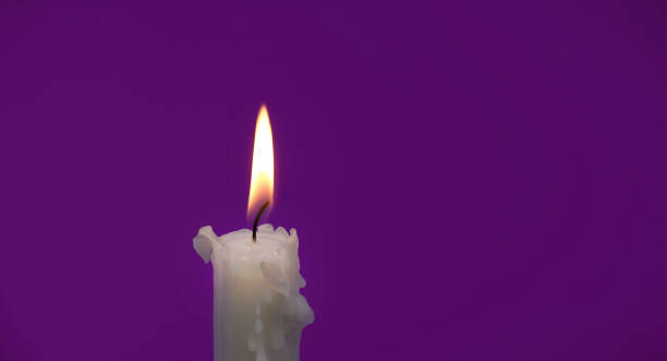 istock Burning wax candle against a purple background 1479911990