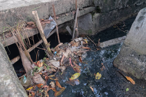 trash stuck in the sewage barrier in the ditch stock photo
