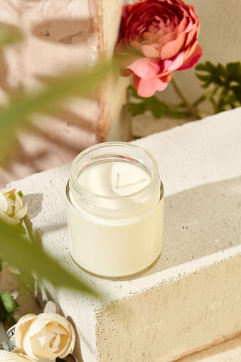 istock Composition with aromatic candle in jar on concrete podium. Mockup soy wax candle in natural style with flower. Scented handmade candle with wick.  Handmade spa product  from soy wax in glass. 1479927773