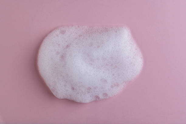istock White cleanser foam bubbles on pink background or texture, closeup, top view. Soap suds or foam and bubbles from detergent or shower gel or shampoo 1479929185