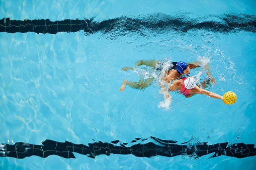 Aerial view of water polo player heavily defending before opponent takes the shot.