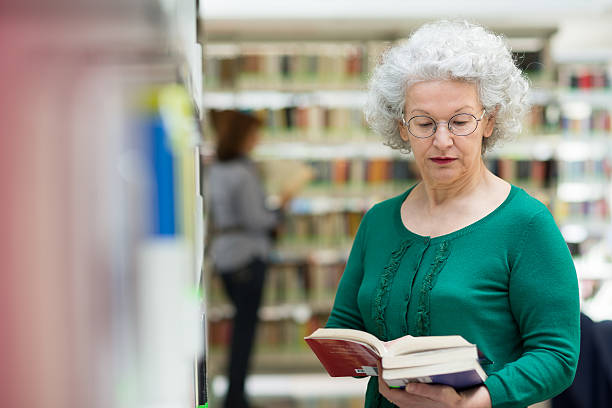 istock senior woman reading and choosing book in library 147993766