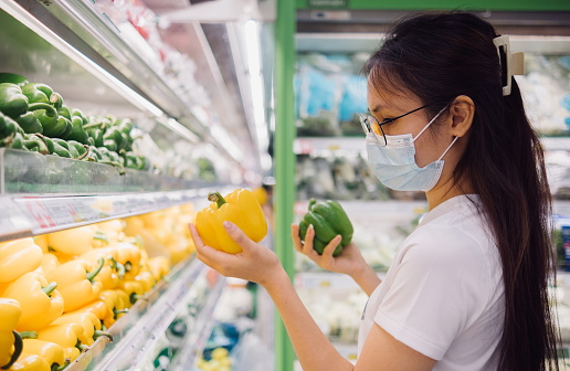 Asian woman in face mask shopping for bell peppers, organic lifestyle and vegan concept.