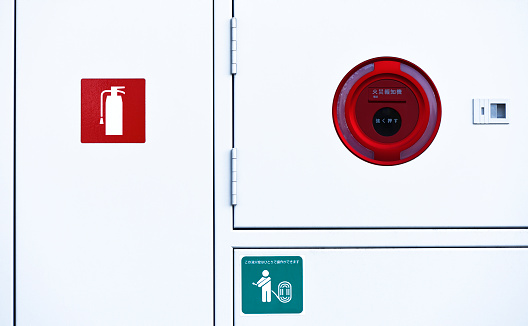 Red Fire Alarm with Emergency telephone on white metal cabinet.