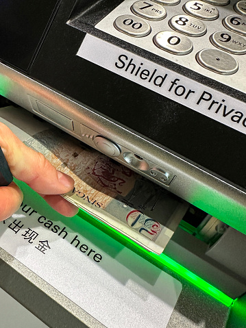 Stock photo showing close-up view of cash withdrawal being removed by an unrecognisable person at a cashpoint (ATM - automatic teller machine). Cash machine fraud is an ongoing problem for banks, with a growing percentage of debit and credit cards being cloned or stolen.