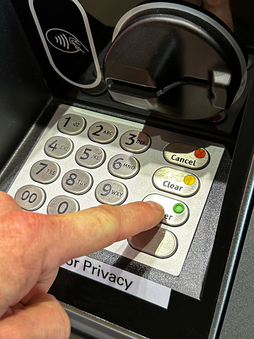 Stock photo showing close-up view of PIN numbers being entered with index finger of unrecognisable person at a cashpoint (ATM - automatic teller machine). Cash machine fraud is an ongoing problem for banks, with a growing percentage of debit and credit cards being cloned or stolen.