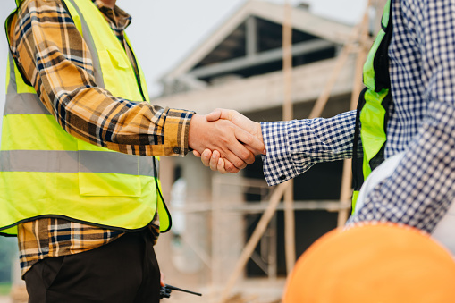 Engineer and contractor join hands after signing contract,They are having a modern building project together. successful cooperation concept in sun light