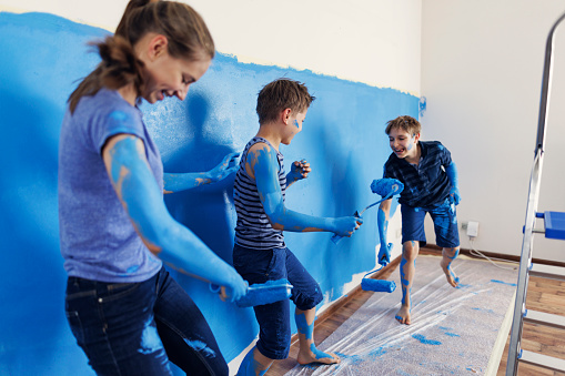 Three teenage kids helping in house renovation. The kids are painting the wall in blue with the paint rollers. During the painting kids are playing and painting themselves.
Shot with Canon R5