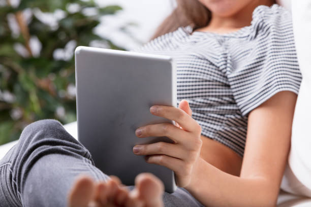 istock Tablet. Unidentified woman using digital tablet on couch with le 1479947171