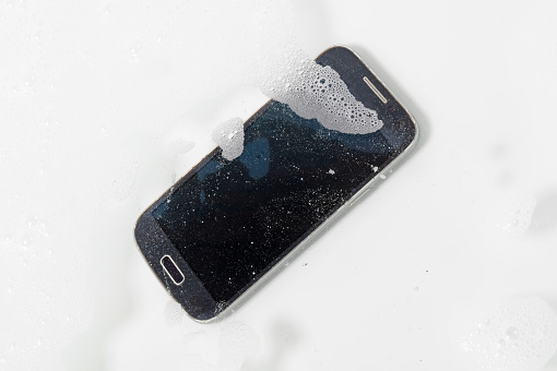 Black smartphone is lying in the water - Fallen in the bathtub
