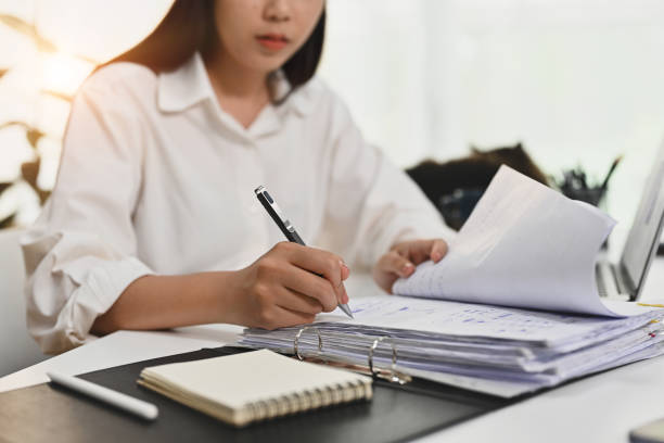 istock Focused female accounting analyst working bookkeeping documents, signing contracts at office desk. 1479951110